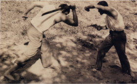 Man with machete fighting other man with revolver